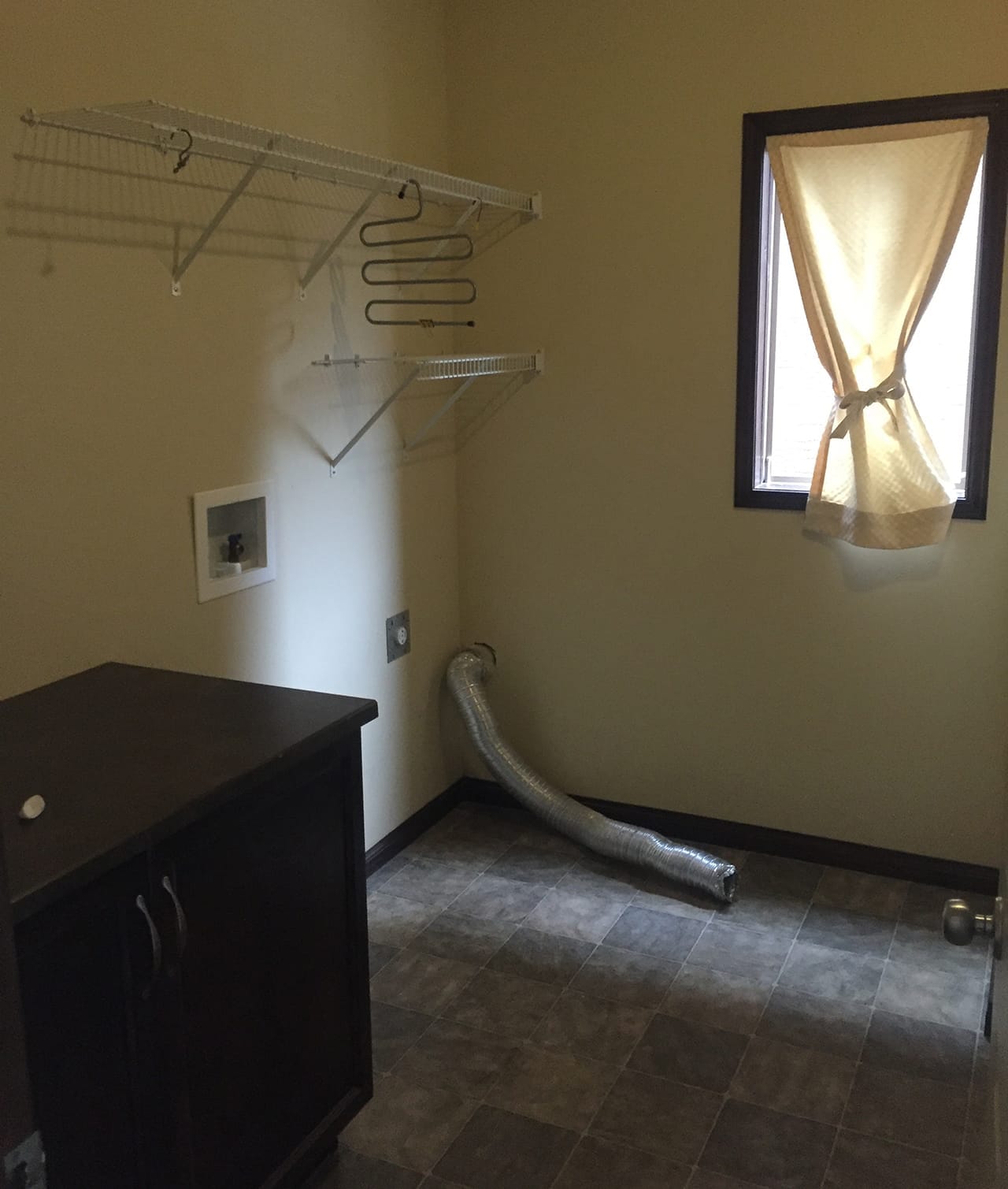 A laundry room with two cabinets and several rows of wire rack shelving.